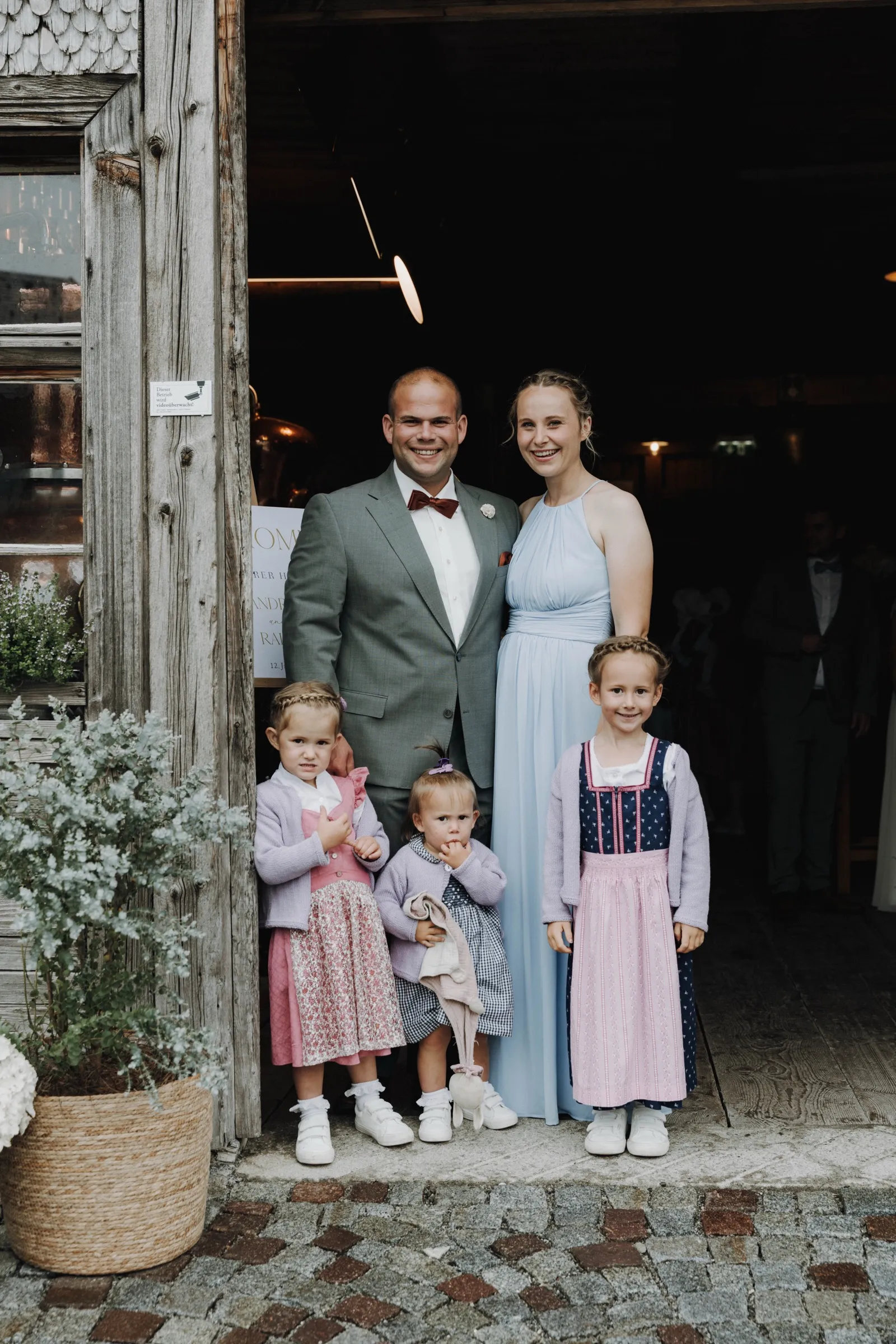 Familienportrait in festlicher Kleidung vor dem Eingang eines alten Holzstadels