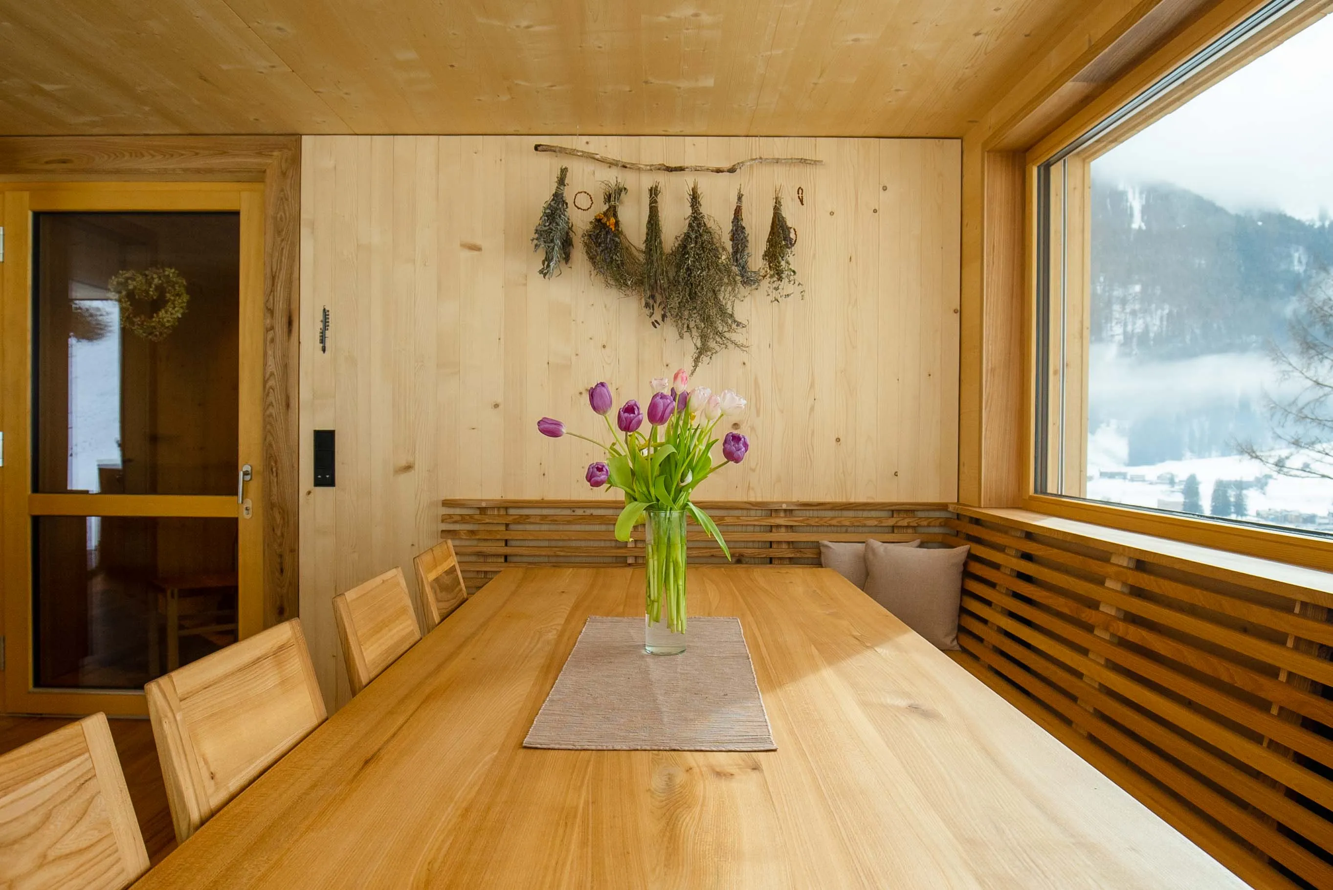 Langer Holztisch im Seminarraum mit Tulpenstrauß und Blick auf die verschneiten Berge